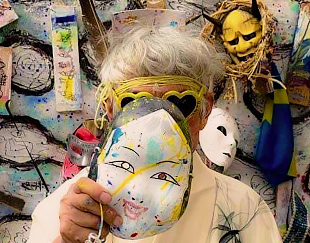 porträtt av Yoshio Nakajima med mask framför en av sina målningar, foto Peter Arnesson
