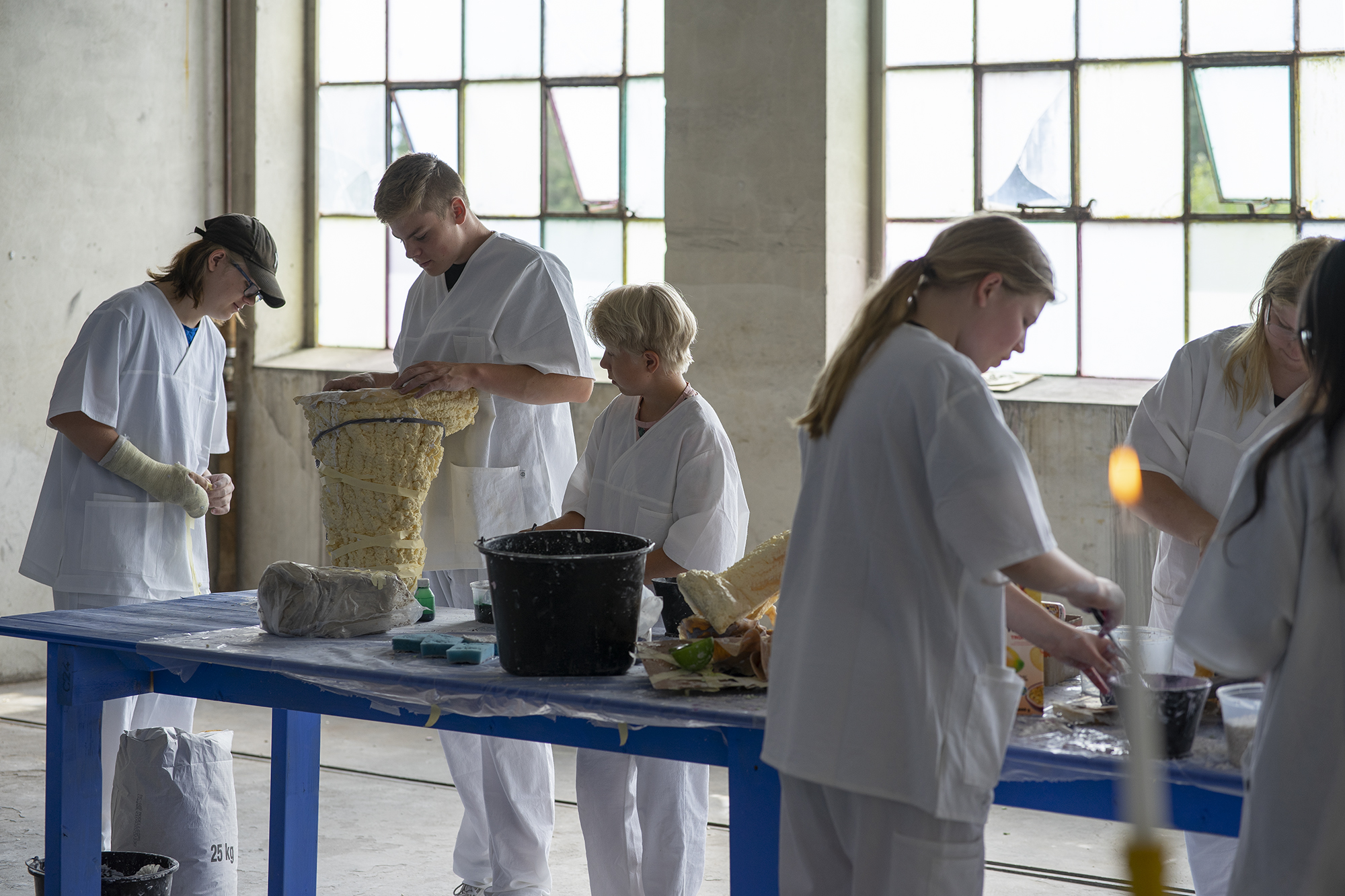 Deltagare i Nina Jensens deltagarpaserade konstverk "orörliga rörare" arbetar i utsällningen "allt kött är hö"